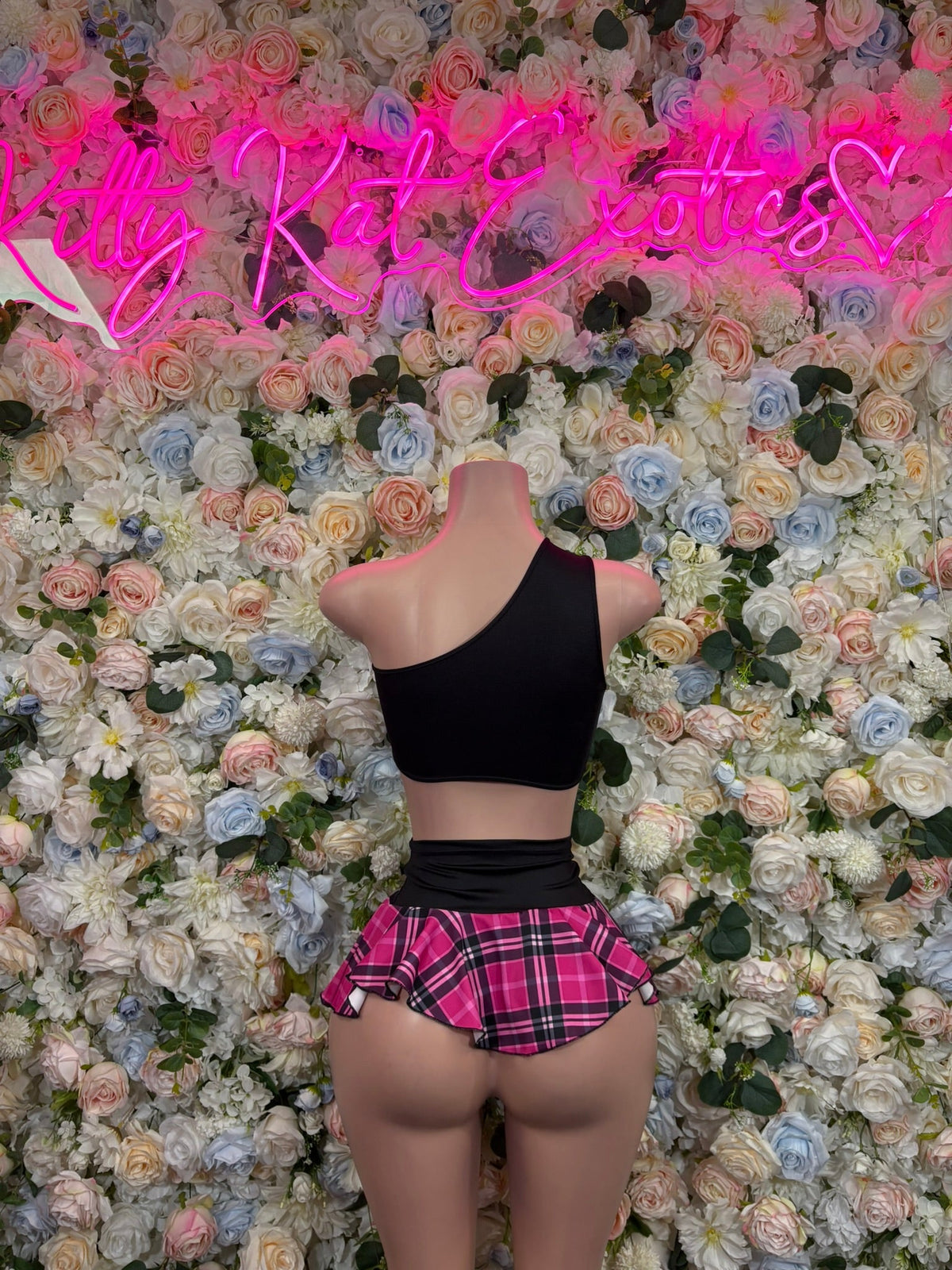 Black asymmetric crop top with pink plaid ruffle mini skirt on mannequin