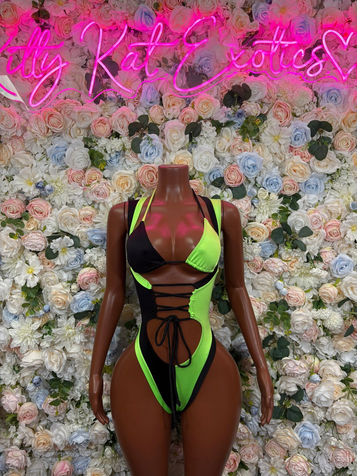 Neon green and black colorblock slingshot bodysuit with lace-up front and cutouts