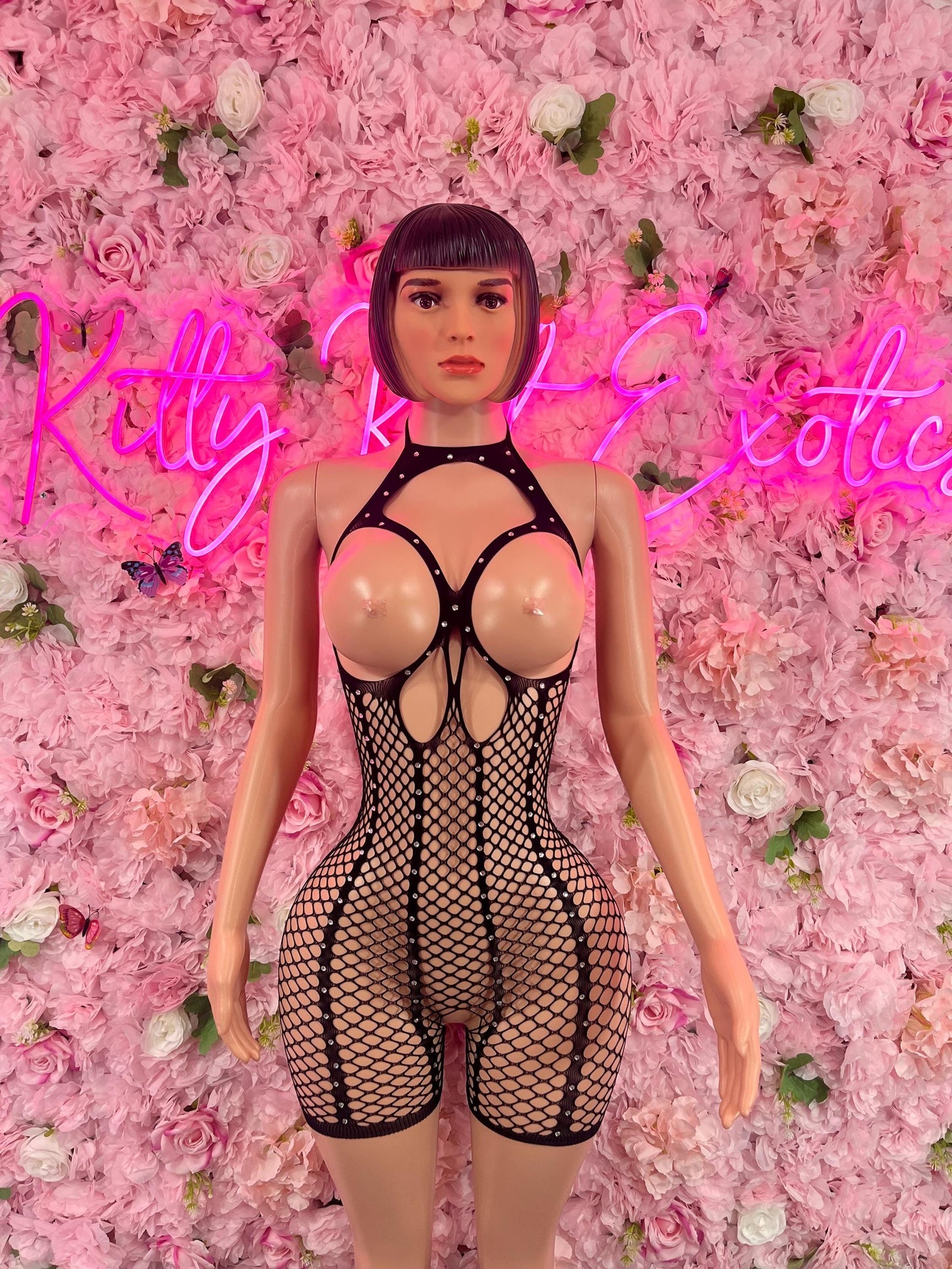 Mannequin displaying Valentines Day One Piece Fishnet Black Dancewear Exotic wear against a backdrop of pink roses and a neon sign.