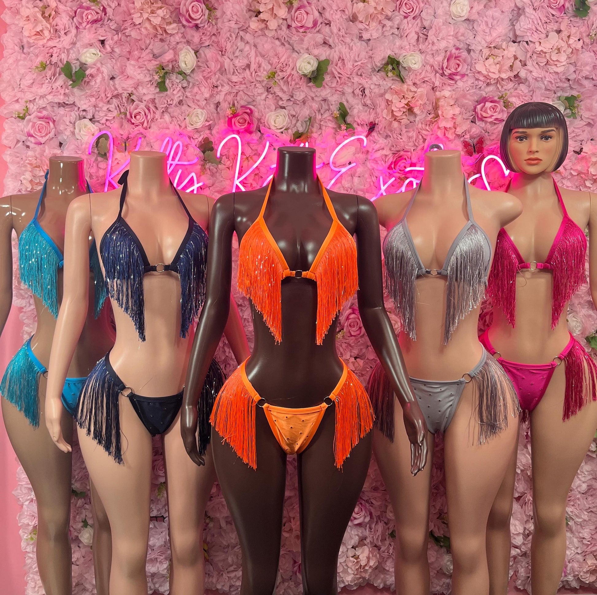 Two-piece fringe bikinis on mannequins, orange centerpiece with assorted colors