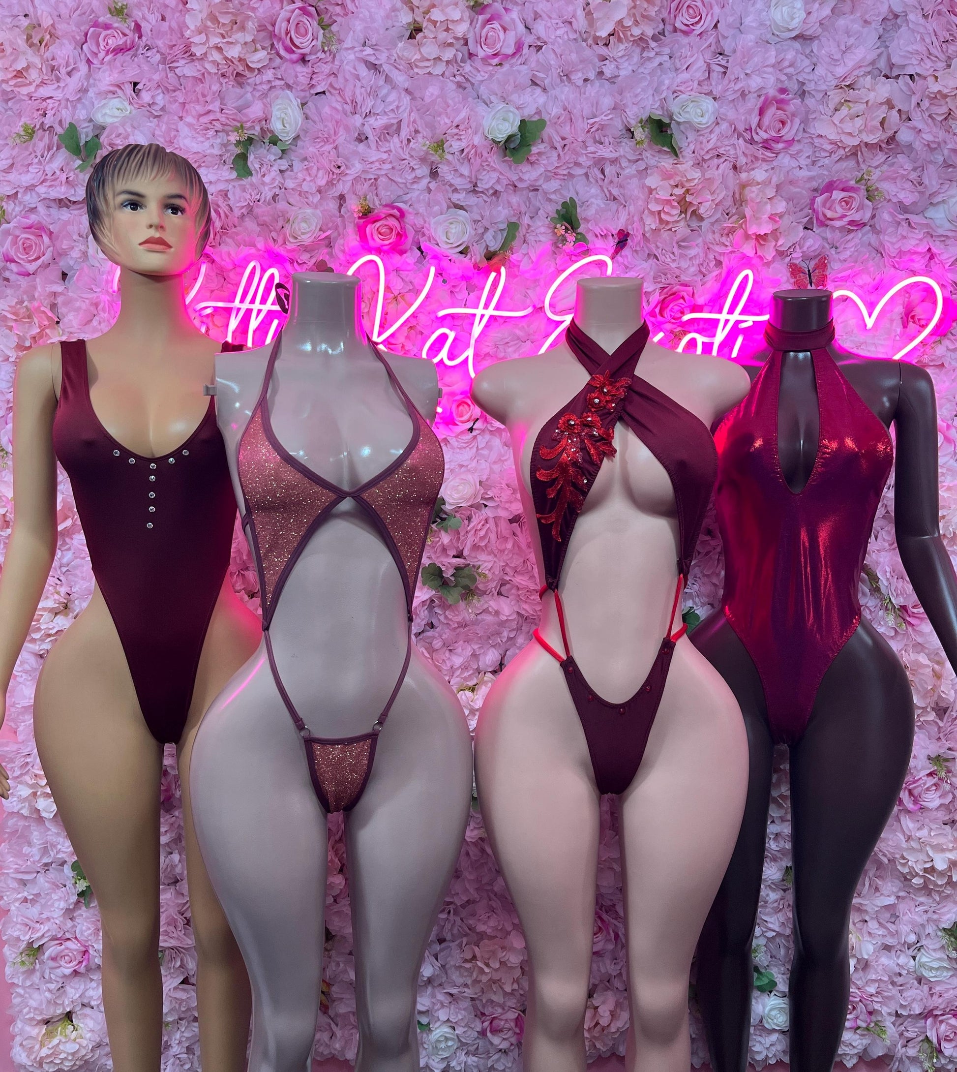 One-piece dancewear bodysuits on mannequins in dark red with sheer panels
