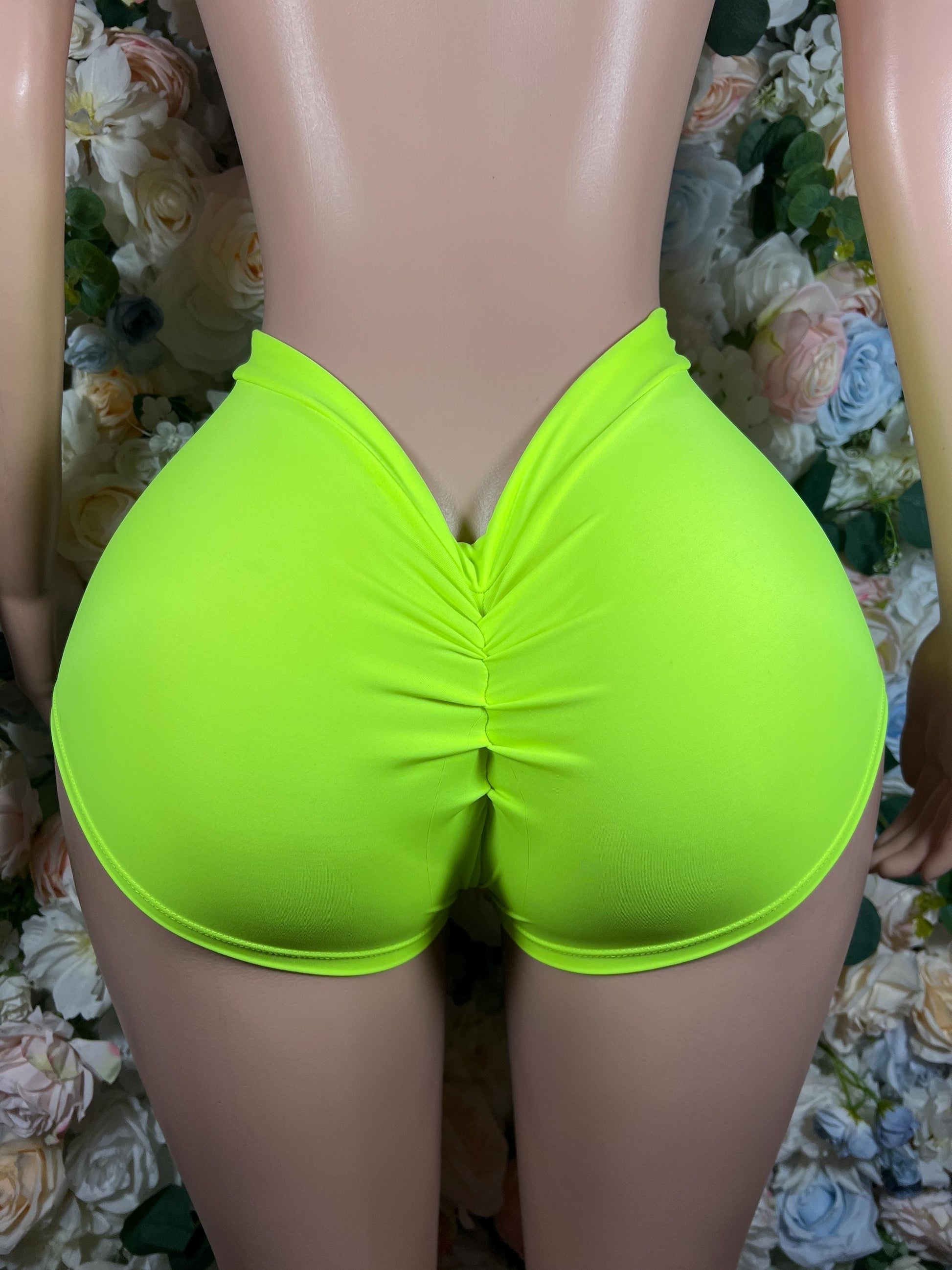 Neon green high-waisted shorts with ruched back seam and curved leg openings