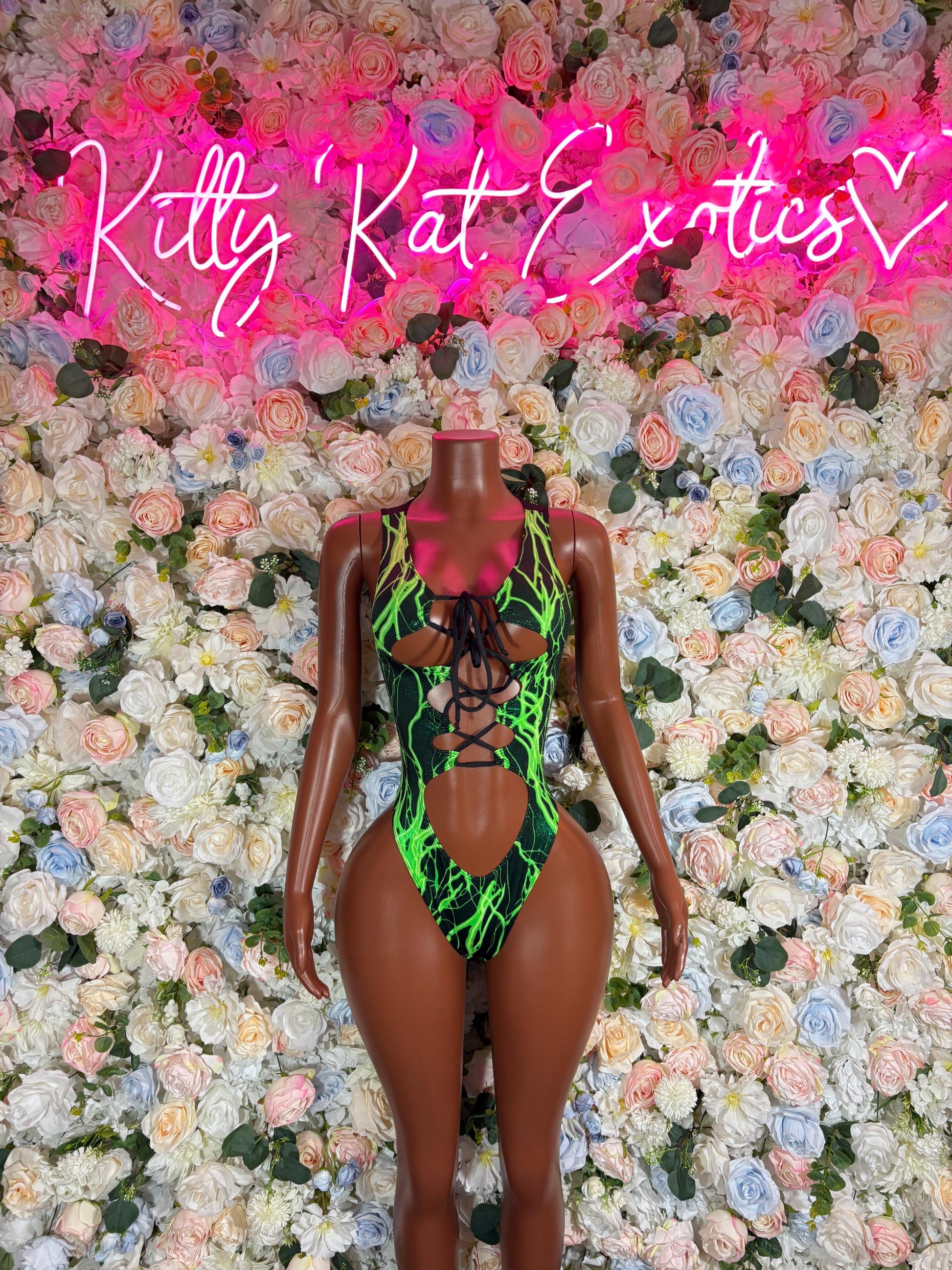Green one-piece bodysuit with crisscross black lace-up straps, front view