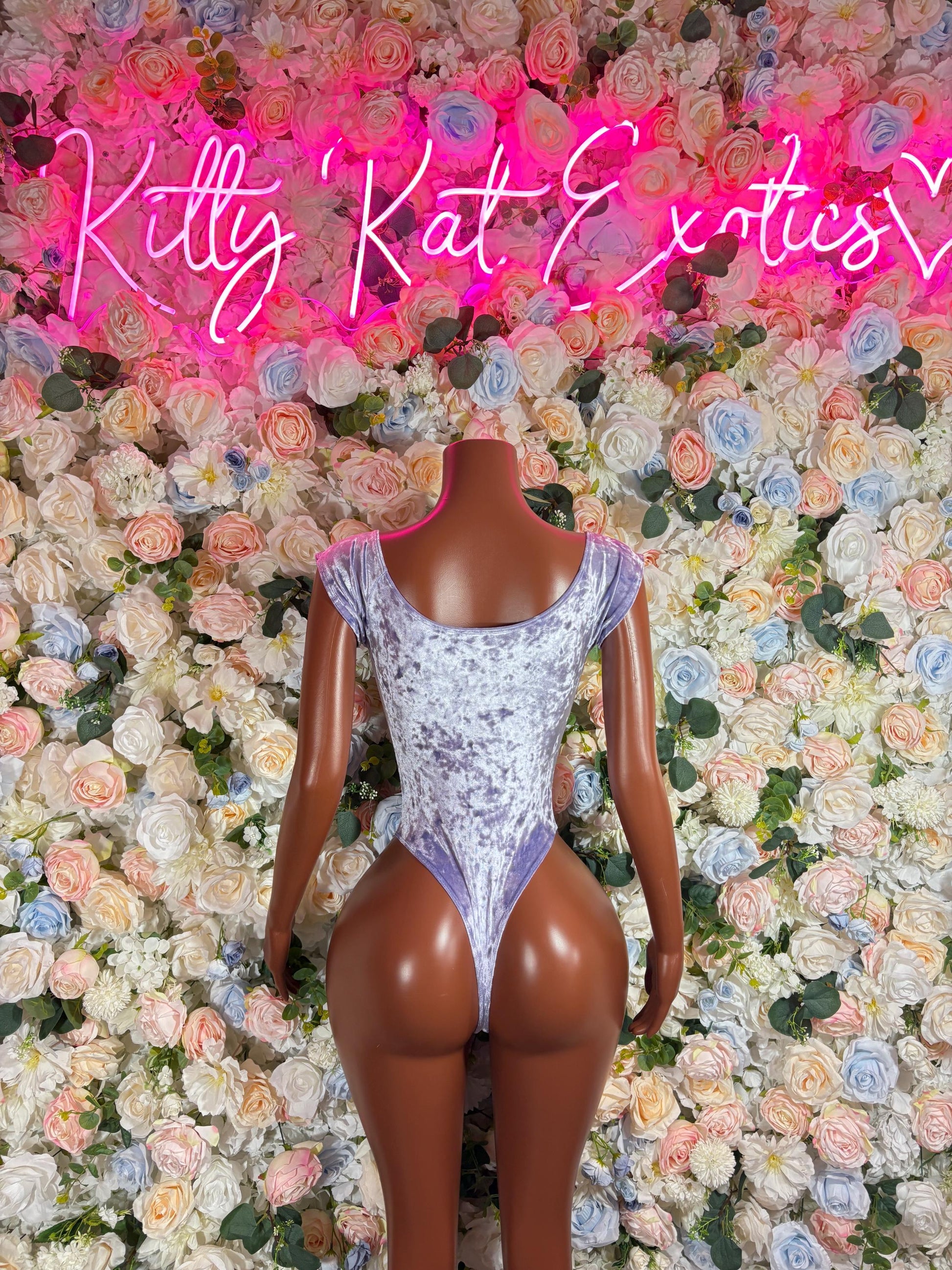 Purple sparkly one-piece bodysuit on mannequin, sleeveless deep V, high-cut legs