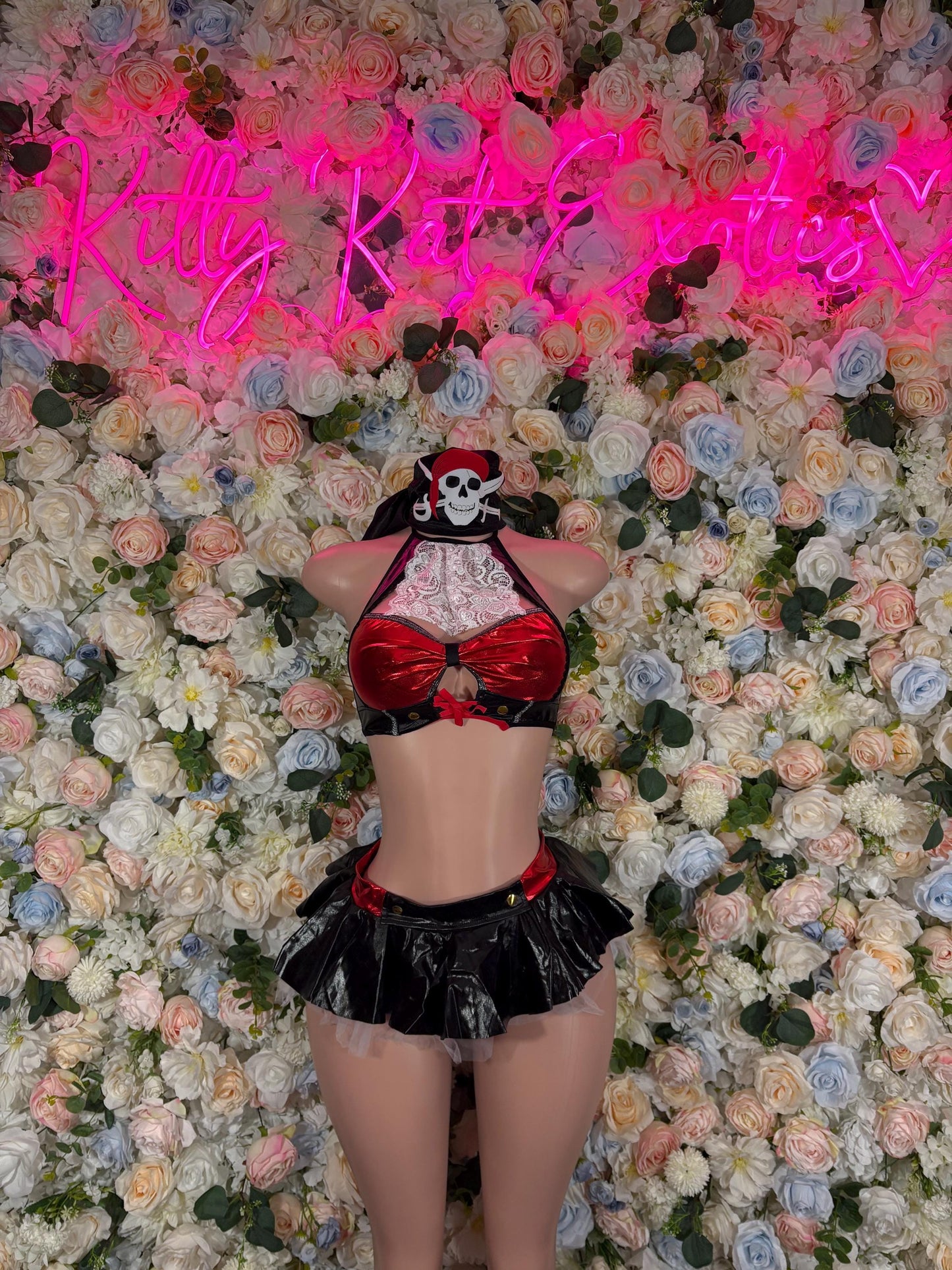 Pirate-style womens costume with skull hat, red bow corset, and black ruffled skirt