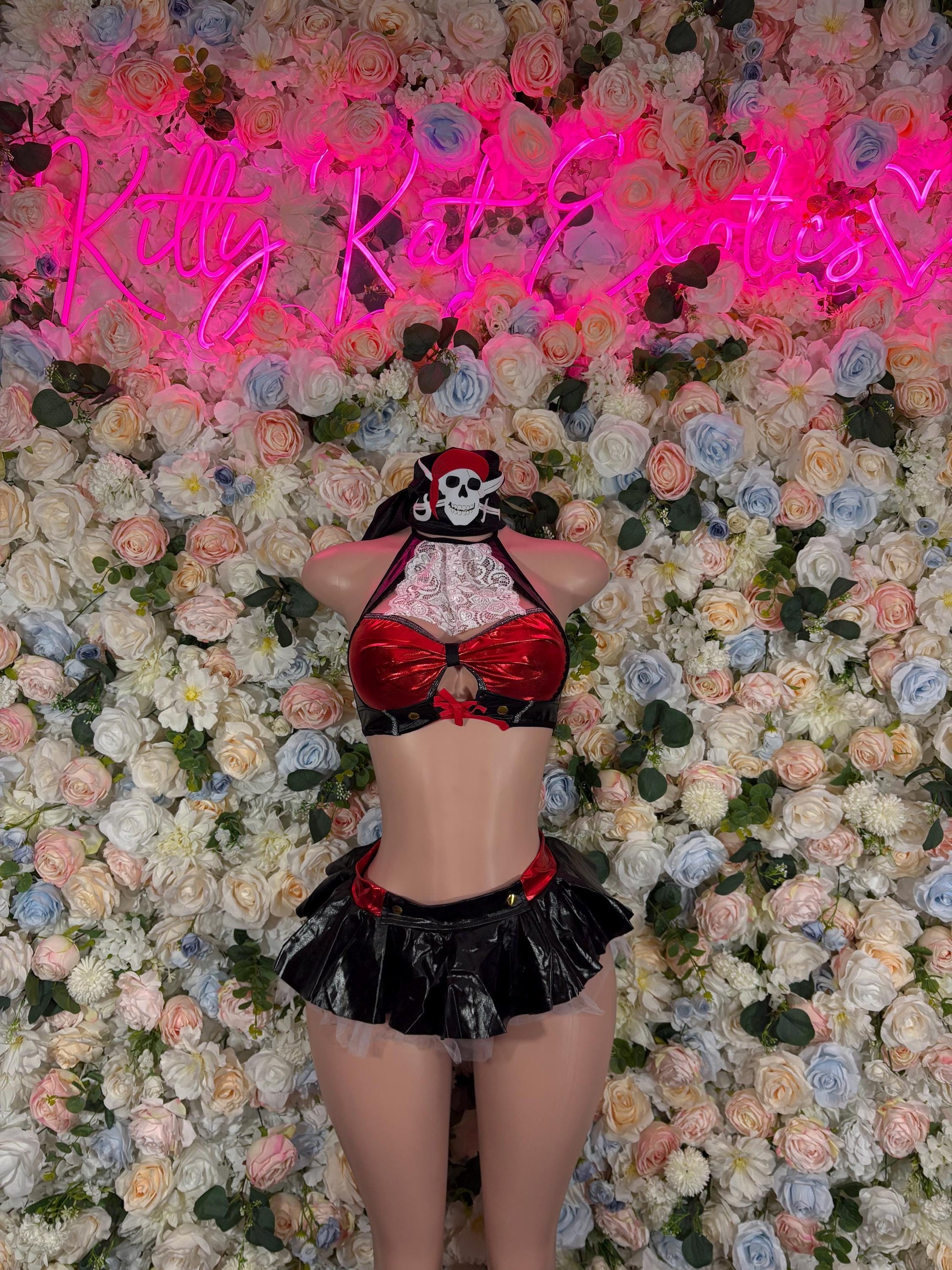 Pirate-style womens costume with skull hat, red bow corset, and black ruffled skirt
