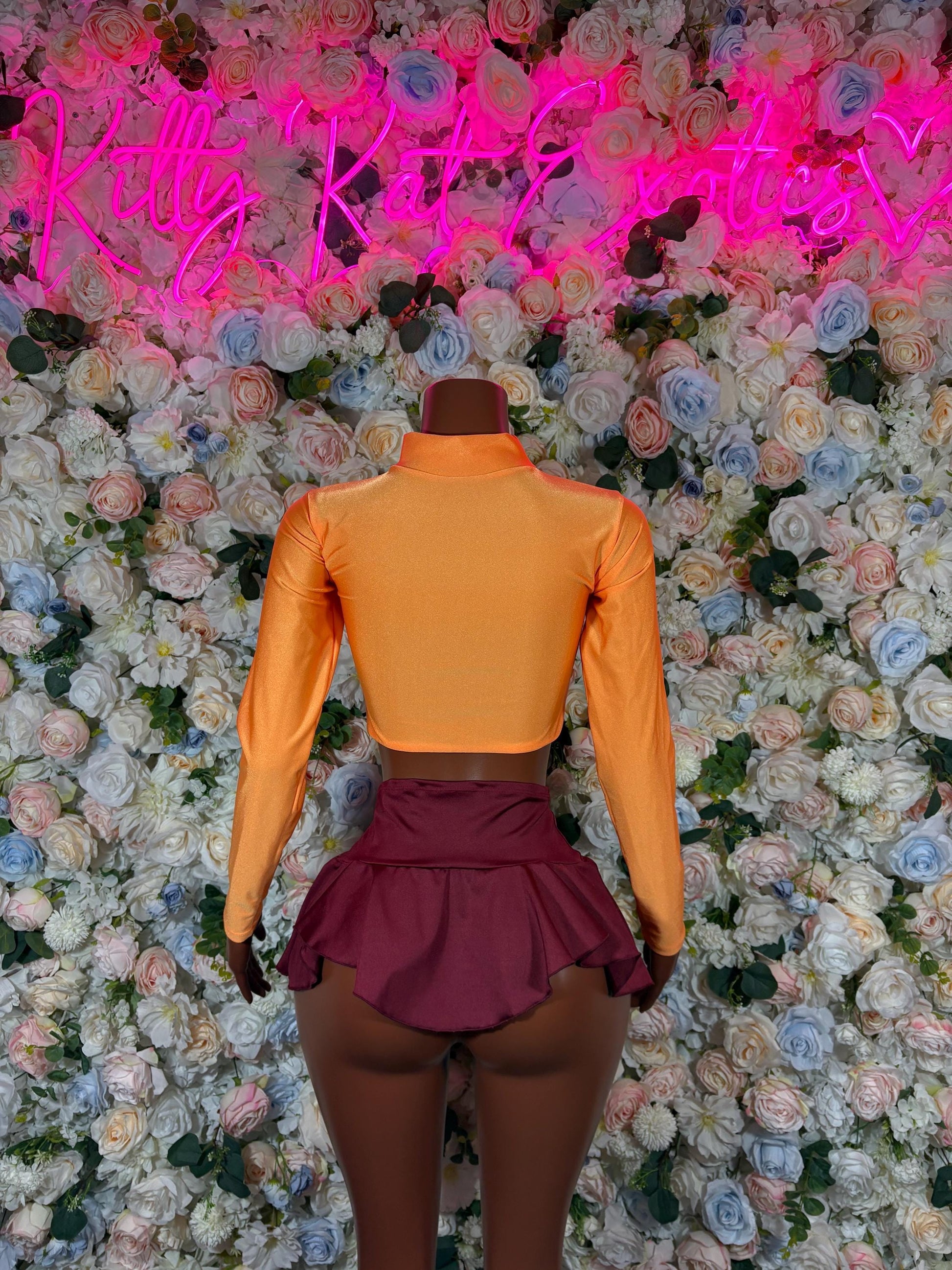 Women’s costume back view: orange turtleneck top with burgundy pleated skirt