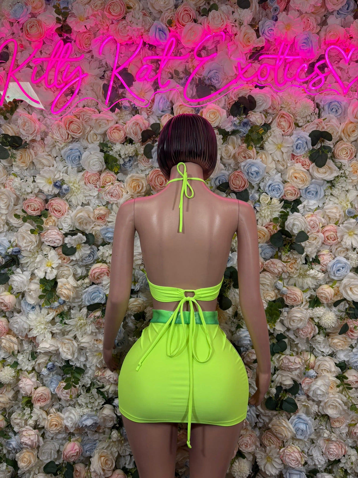 Neon lime green back-tied halter top and ruched mini skirt, back view
