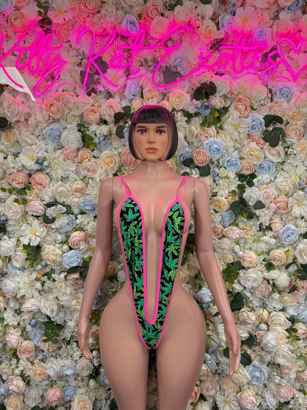 Deep-plunge slingshot bodysuit in pink with green graphic panels, front view