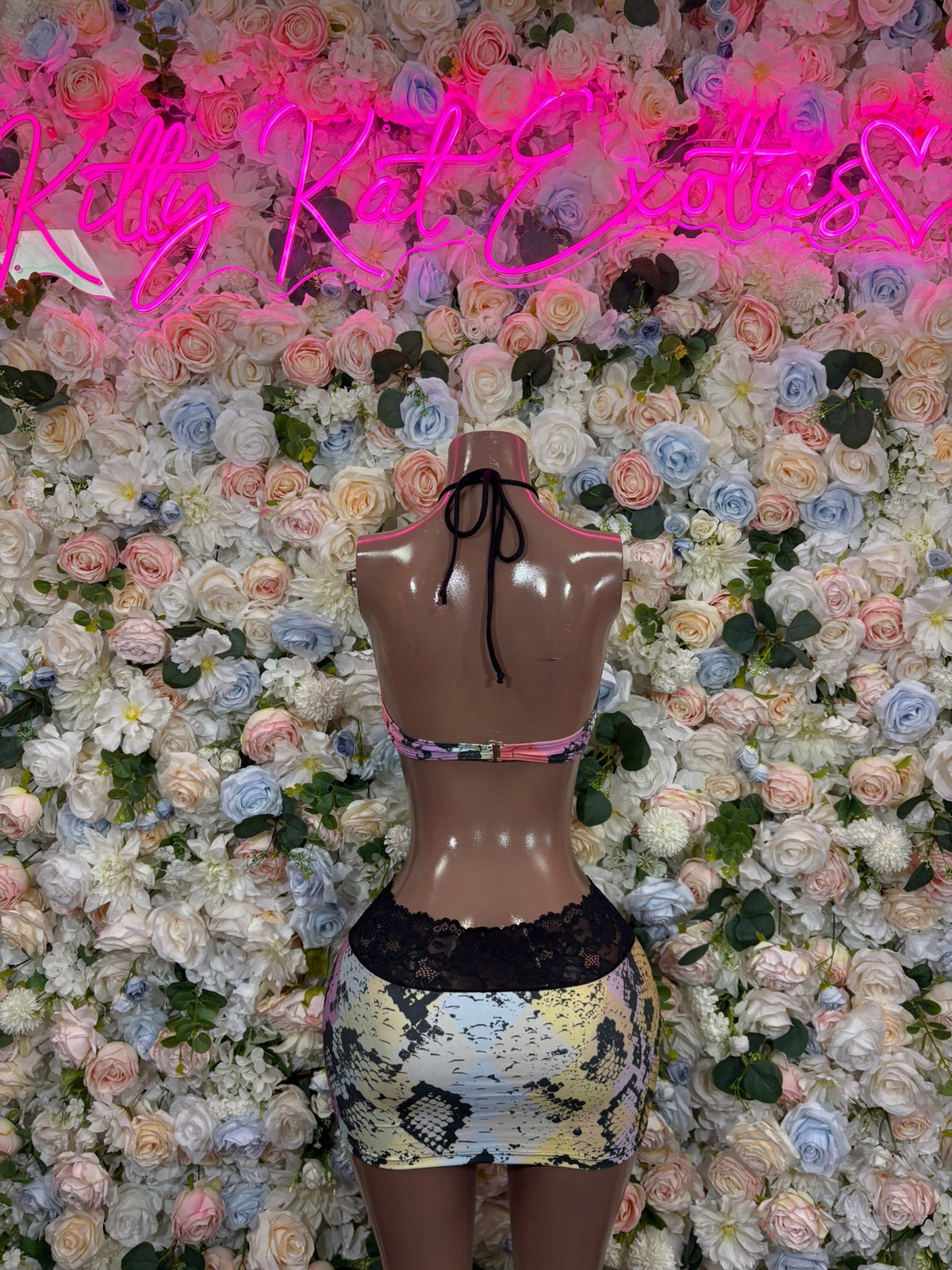 Pastel snake-print halter top and lace-trim mini skirt set on mannequin, back view.