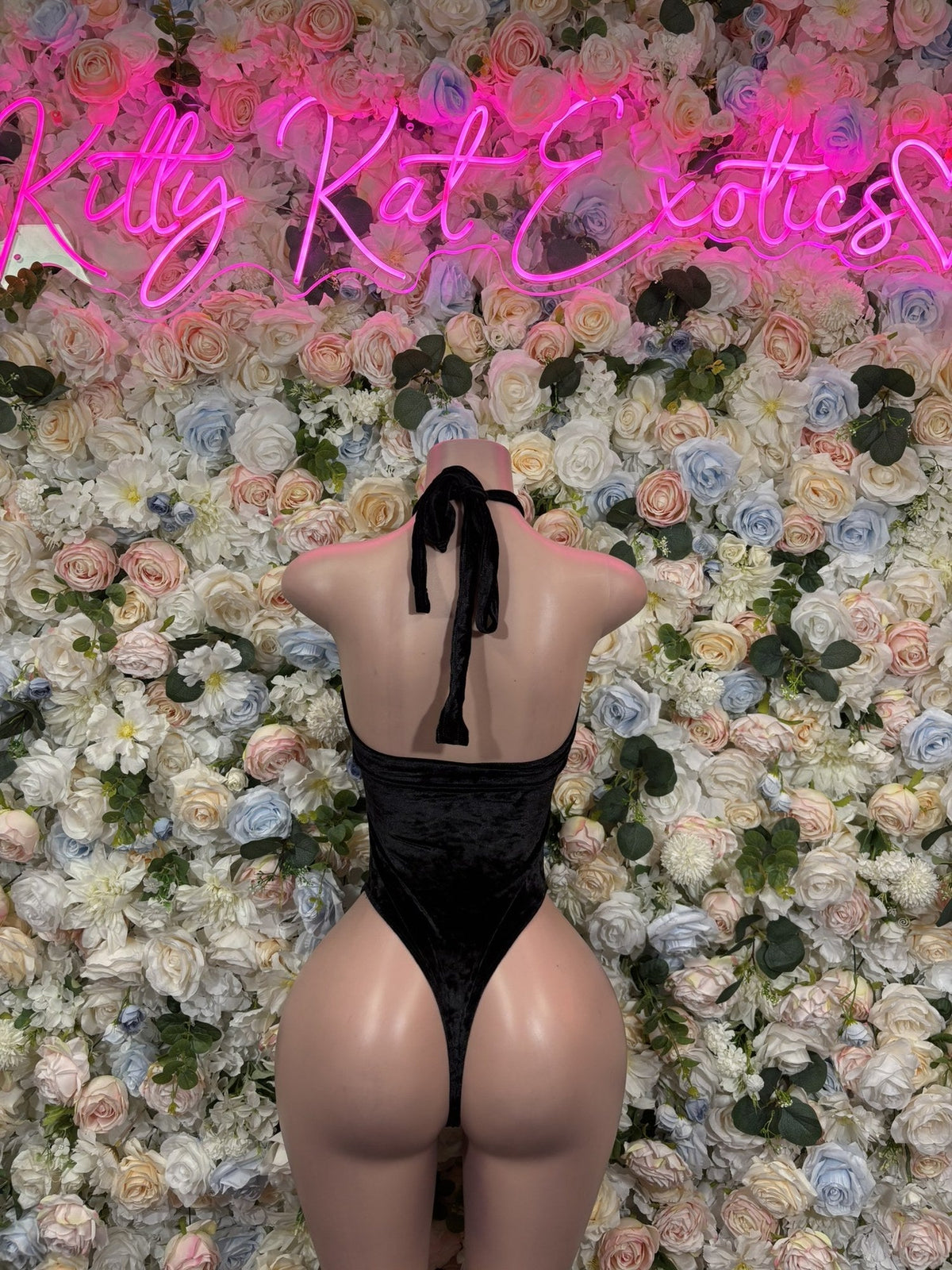 Back view of a black halter bodysuit with tie straps and an open back