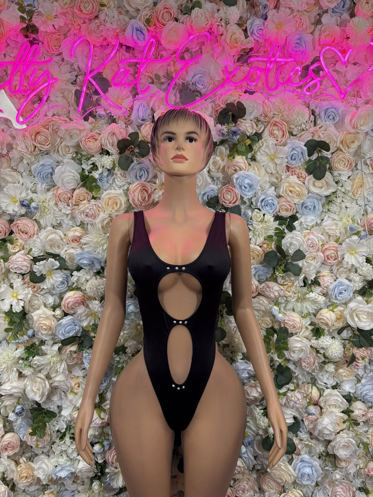 Black cutout bodysuit with ring-front detailing and wide shoulder straps, shown from the front