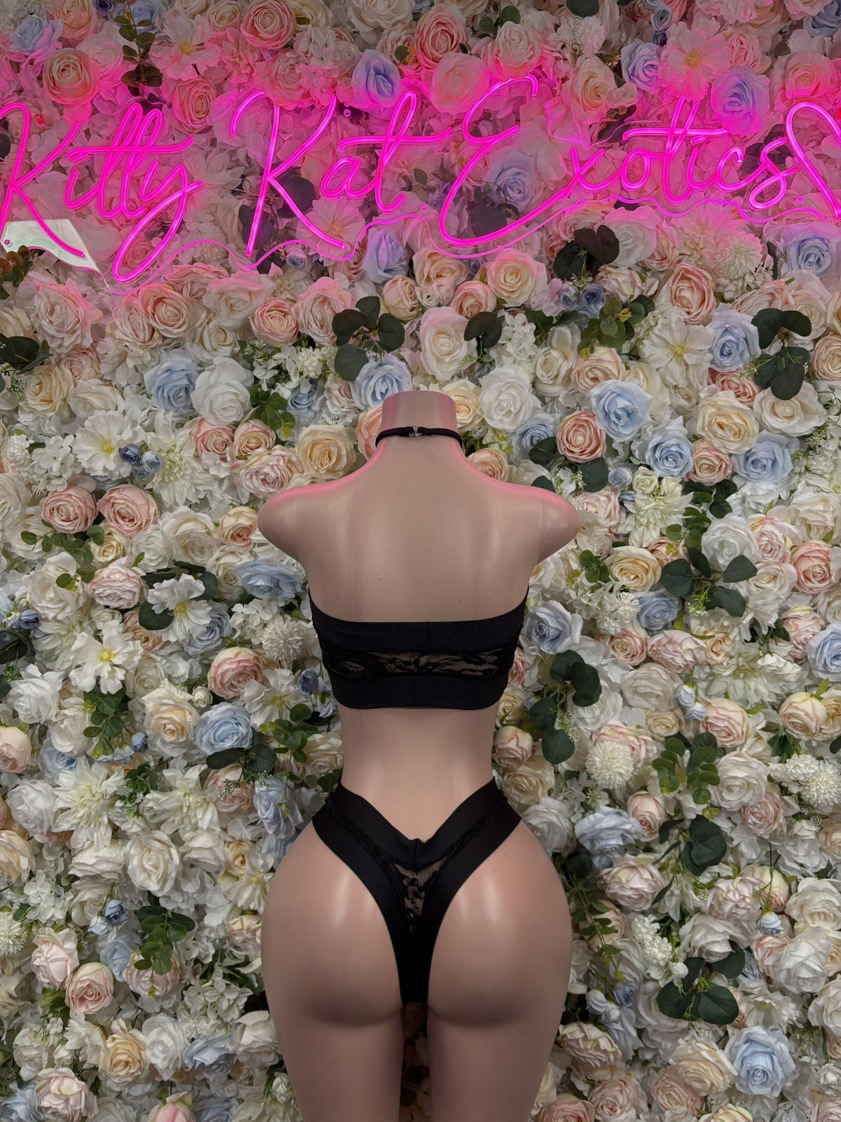 Back of a black lace-up cutout bodysuit with a lace bandeau and high-cut thong bottom.