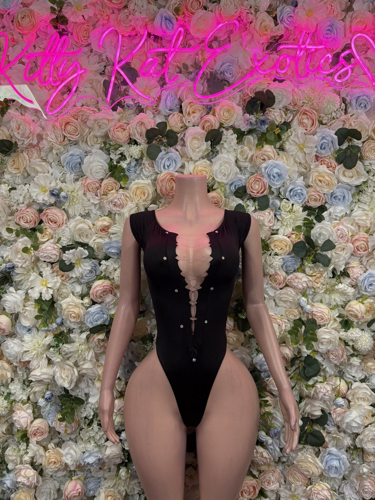 Black long-sleeve bodysuit with a deep V neckline, sheer lace inset, and decorative buttons.