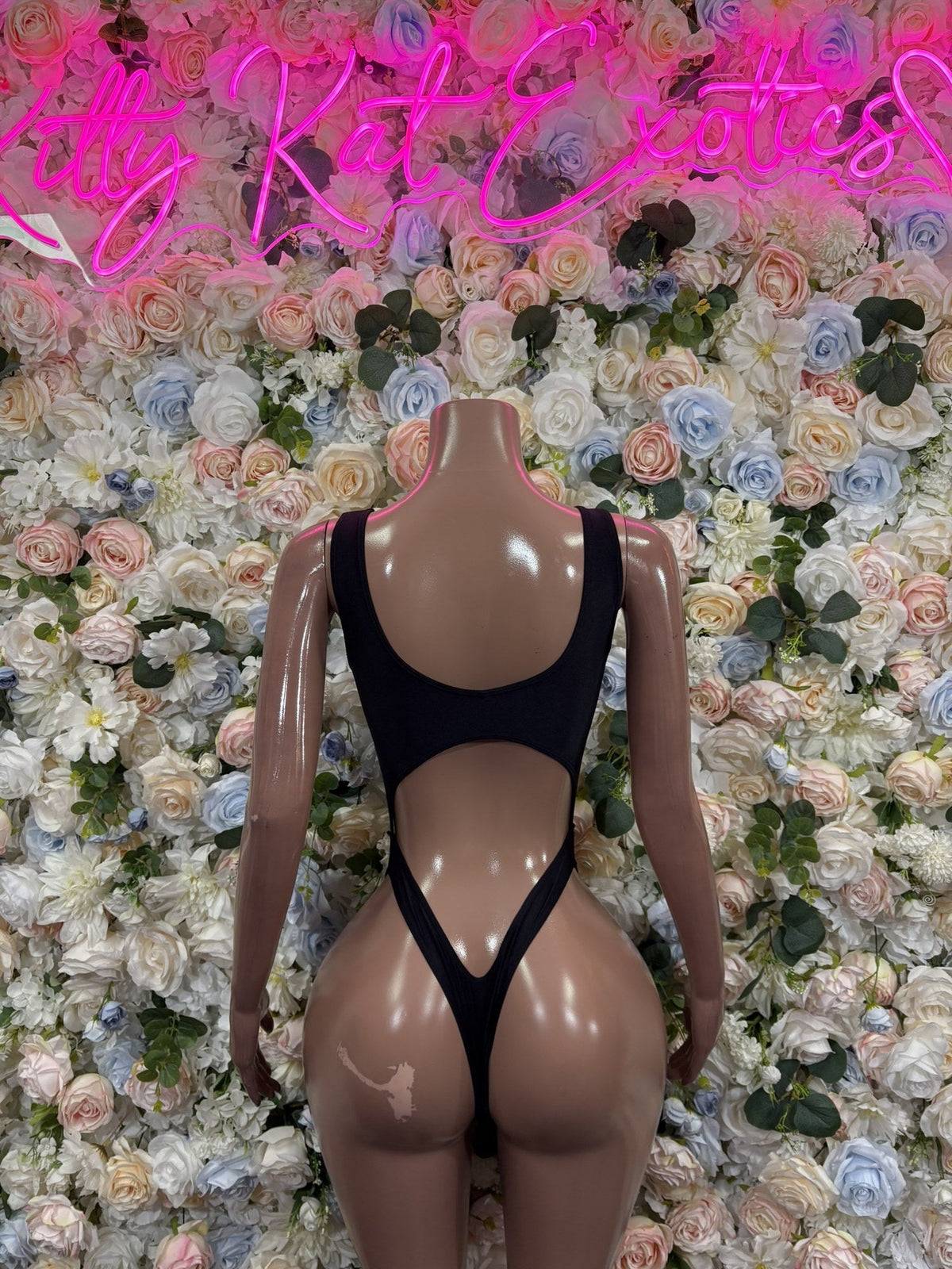 Black open-back bodysuit with wide straps and a low, narrow back; rear view