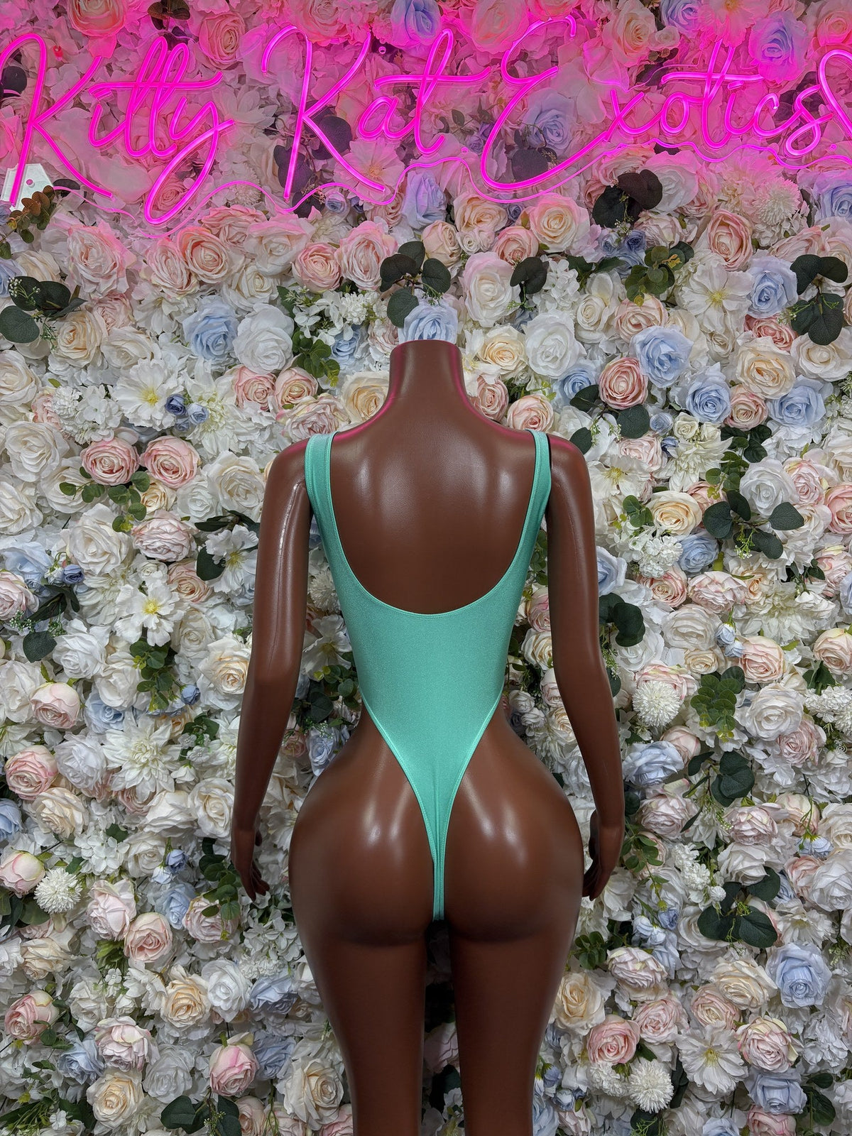 Back of a mint green one-piece swimsuit with a deep scoop back and high-cut legs