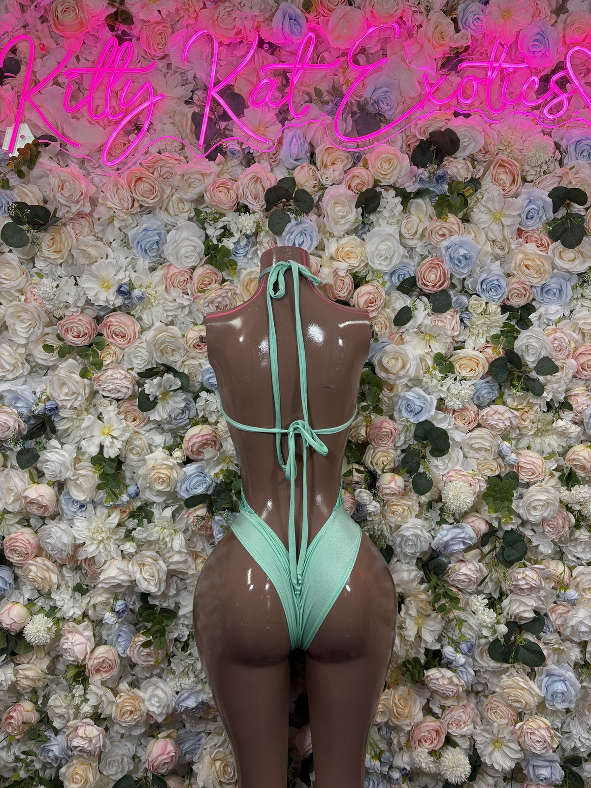 Mint green lace-back bodysuit with thin straps and an open back tied at the neck and waist.