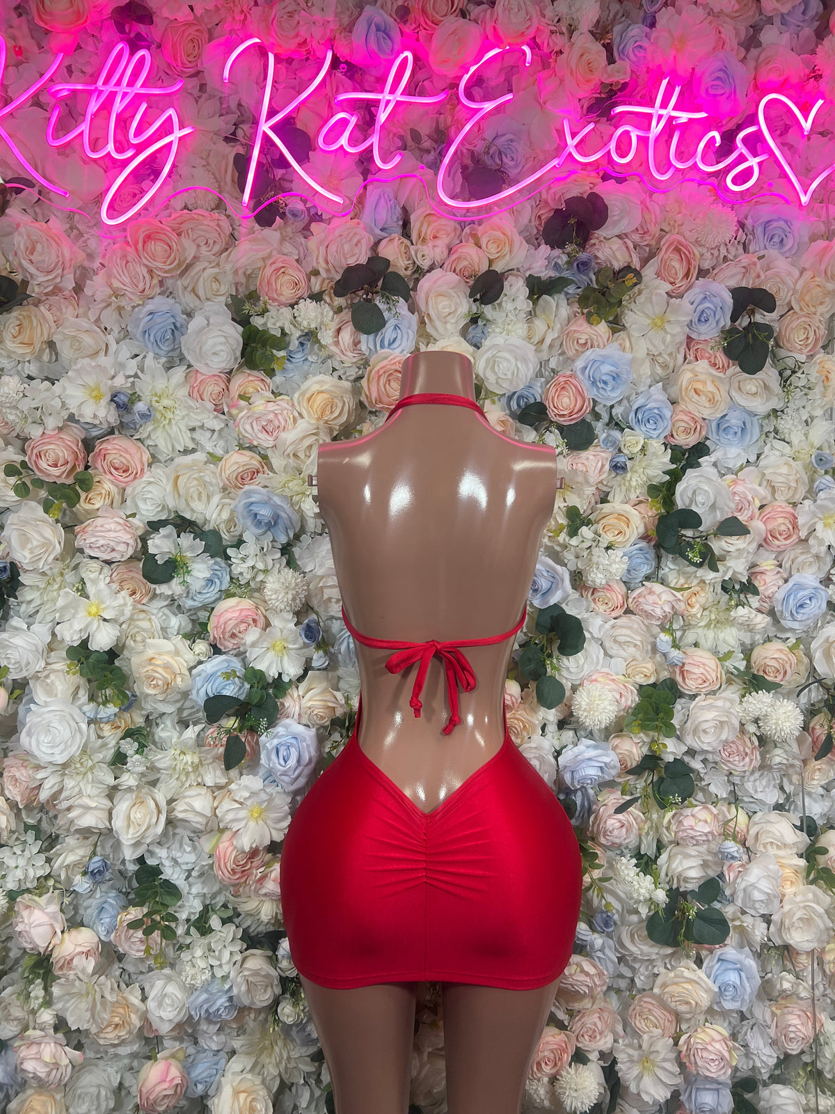 Red ruched mini dress with open back cutout and halter tie straps on mannequin