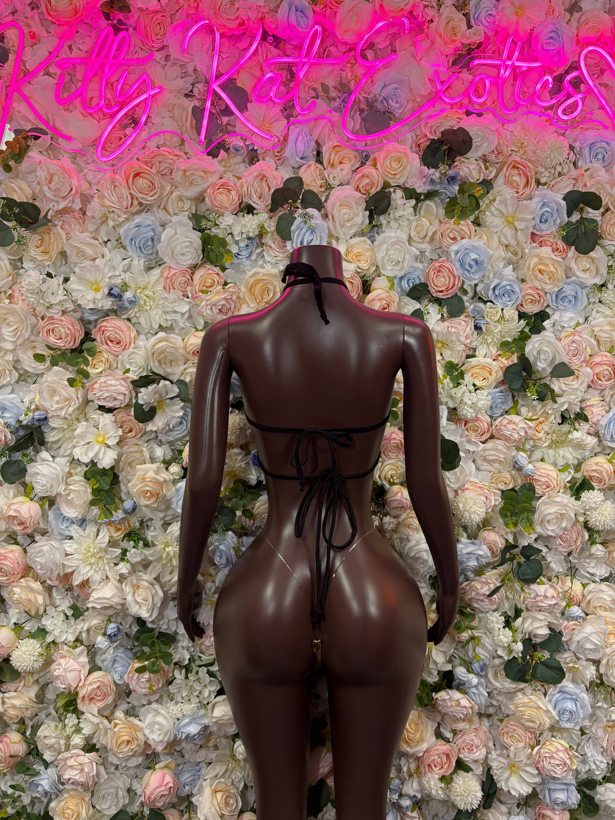 Back-view dark bodysuit with metallic gold trim, crisscross harness straps and tie